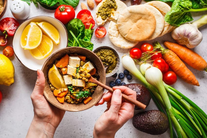 frutas, legumes e vegetais como cenoura, tomate e aipo sobre uma mesa branca.
