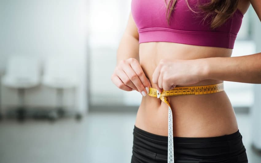 mulher magra com fita métrica na cintura