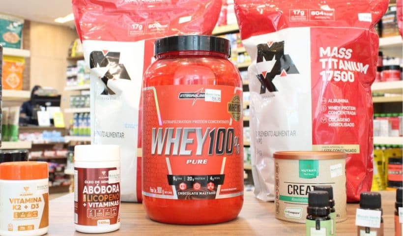 suplementos com whey protein, creatina e vitamina K2 em cima de uma bancada de loja